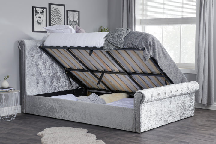 Gray upholstered bed with raised headboard in a bedroom setting.