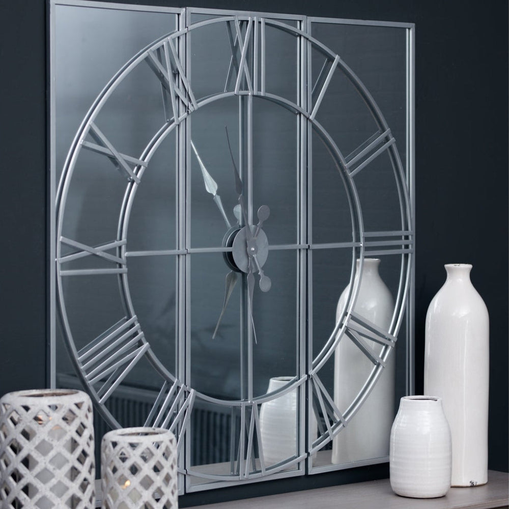 Decorative wall mirror with Roman numeral design on a dark wall with white vases.