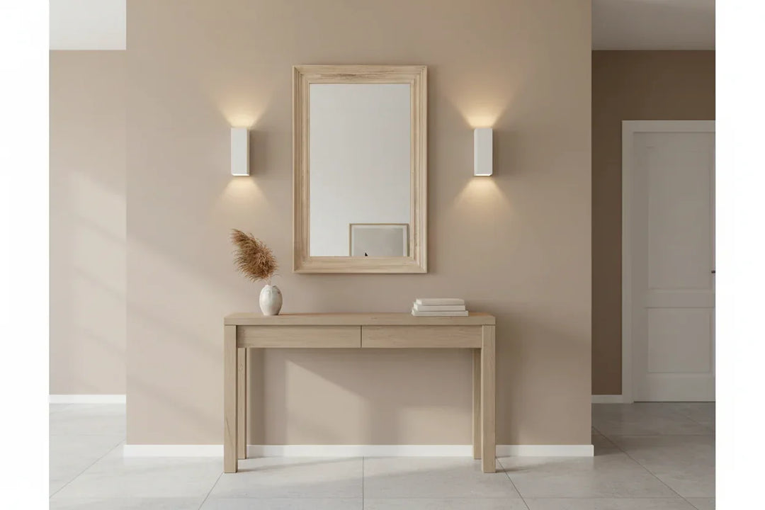 Wooden console table with mirror and decor items against a beige wall.