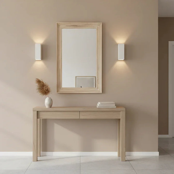 Wooden console table with mirror and decor against a beige wall