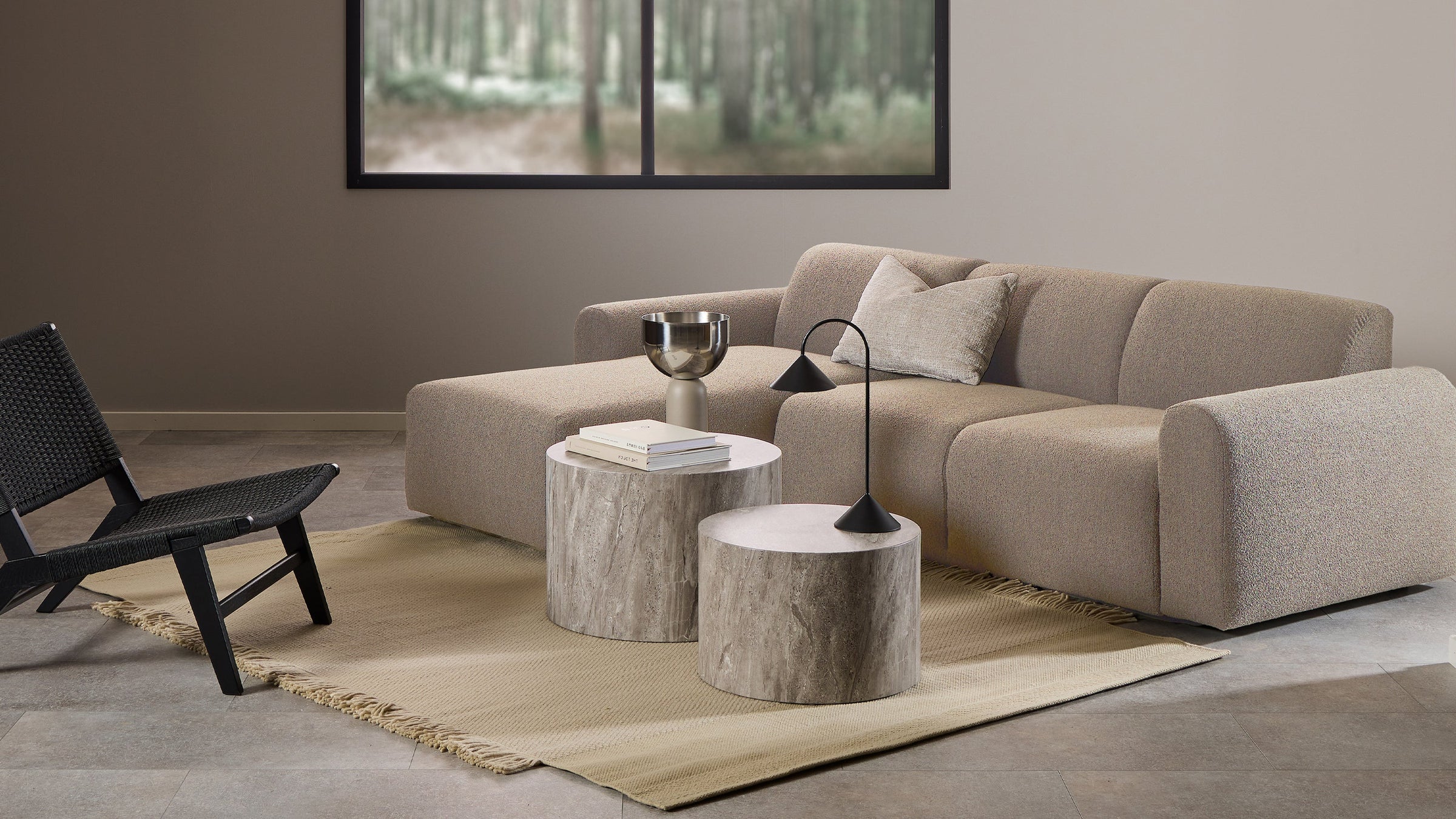 Modern living room with a beige sectional sofa, black chair, and abstract art on the wall.