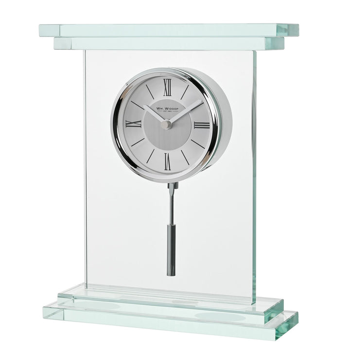 A modern glass and metal mantel clock with a clear rectangular glass frame, a silver-toned round clock face with Roman numerals, and a hanging pendulum, shown on a white background.