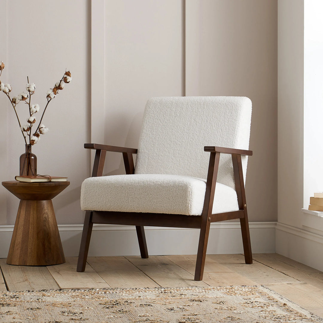 White armchair with wooden frame in a room with light-colored walls and a window.