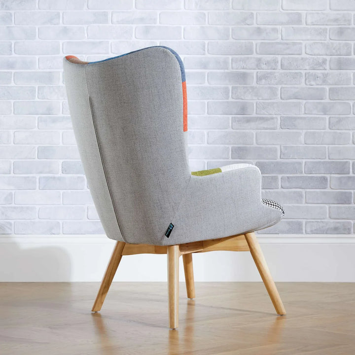 Gray armchair with wooden legs against a white brick wall.