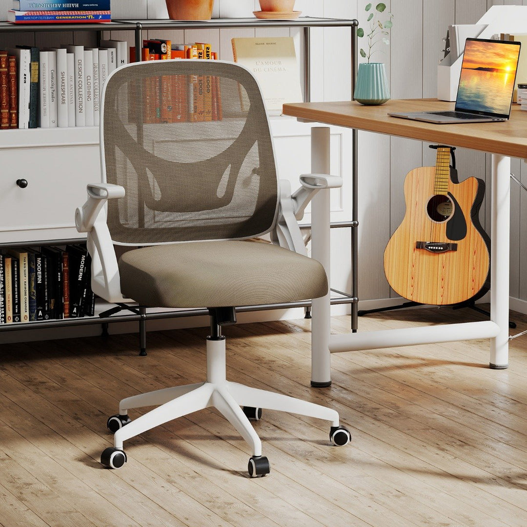 Modern ergonomic office chair in workspace with books and guitar