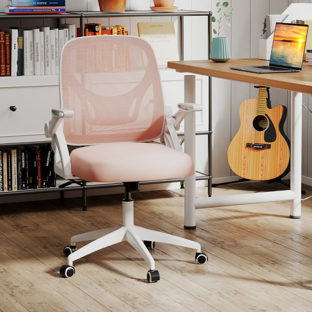 Pink ergonomic mesh office chair in workspace with books and guitar